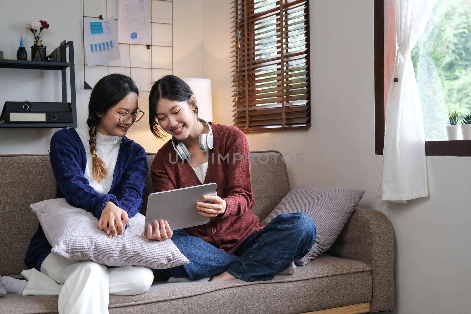 Asian beautiful lesbian women couple hugging girlfriend in living room. Attractive two female gay friend sitting on sofa in living room, feel happy and enjoy spending time together on holiday in house.