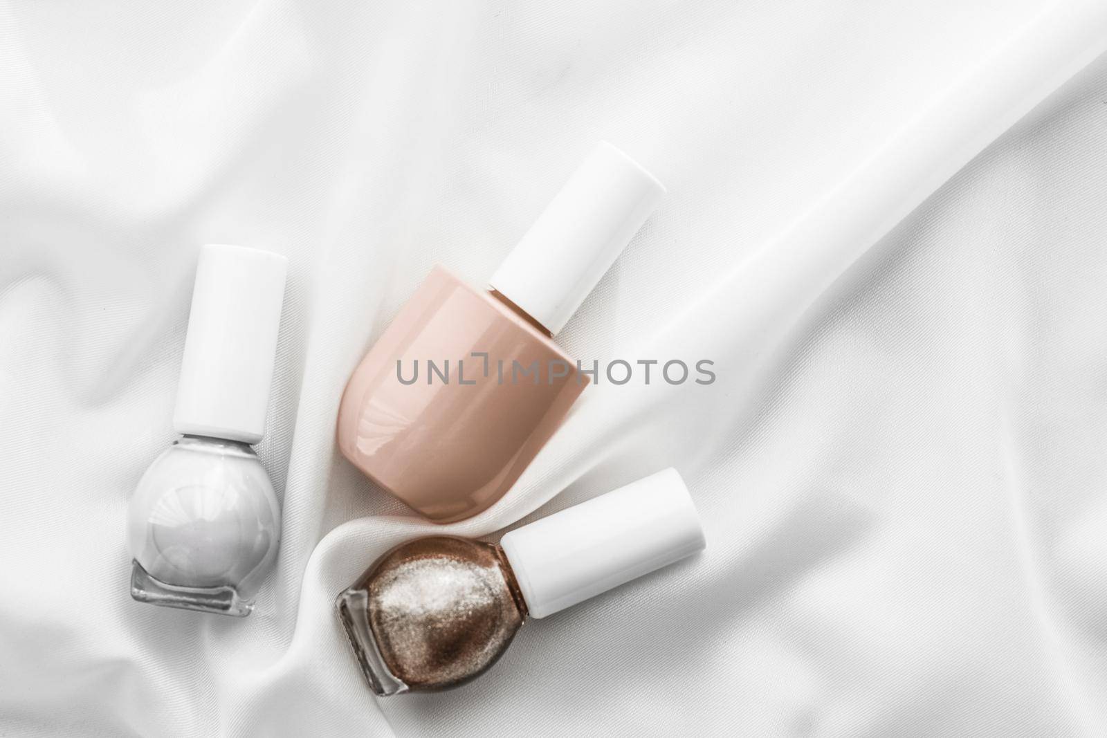 Cosmetic branding, salon and glamour concept - Nail polish bottles on silk background, french manicure products and nailpolish make-up cosmetics for luxury beauty brand and holiday flatlay art design