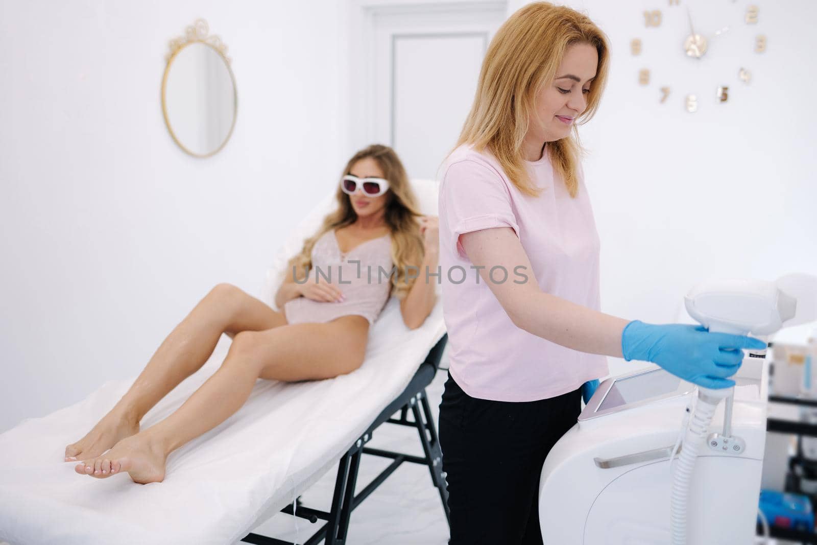 Beautician doing epilation on beautiful woman's leg in mediacl center. Female receiving laser light hair removal treatment for hairless smooth skin at cosmetology salon.