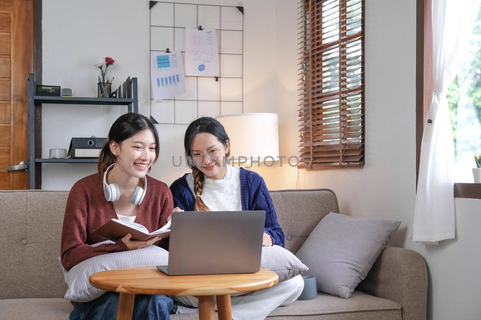 Two asian students learning together online with a laptop and tutor together at home. by wichayada