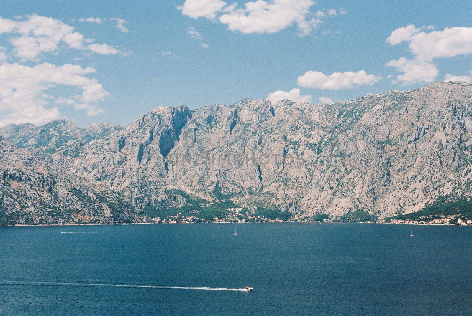 Motor boats float on the blue sea against the backdrop of a high mountain range. High quality photo