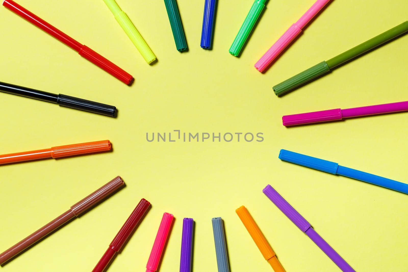 multicolored markers for drawing on a yellow paper background
