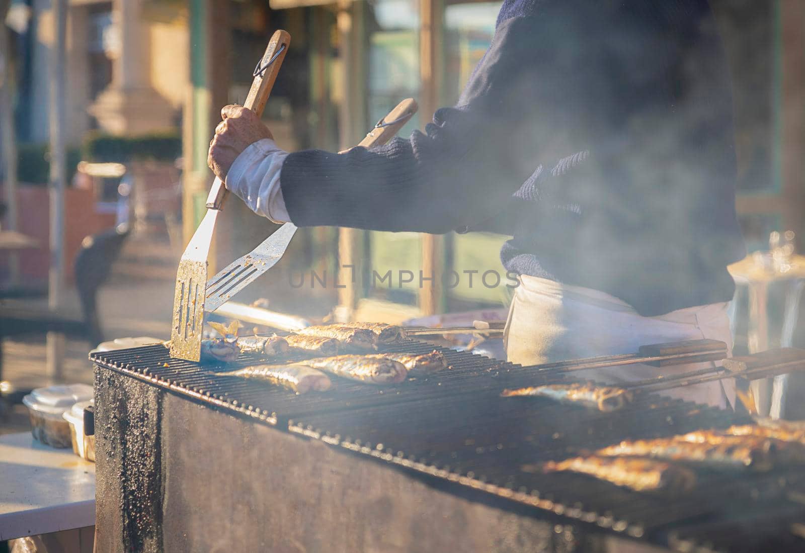 Man cooks herring on the grill on a street market