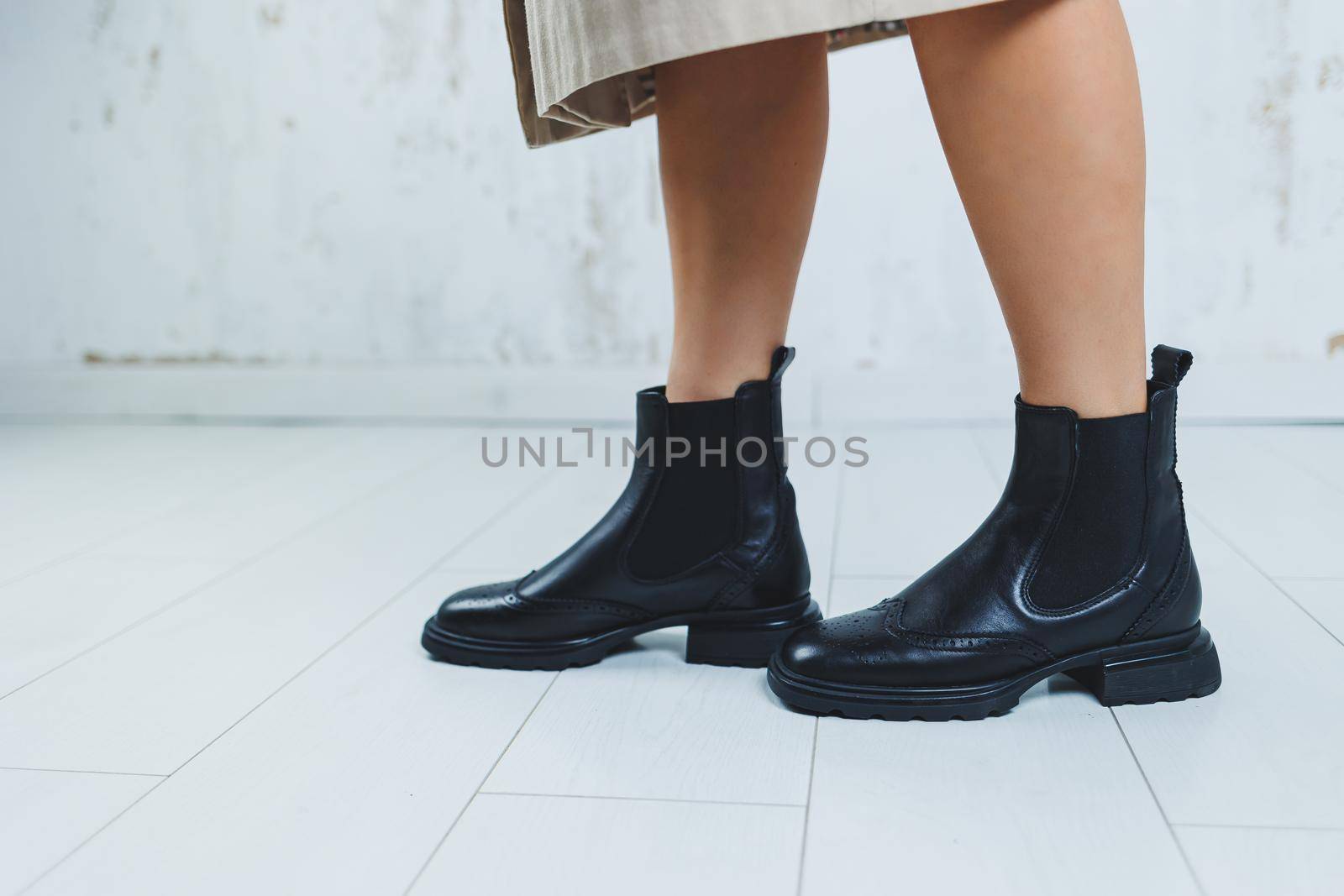 Close up of female legs in black leather Chelsea boots. New autumn collection of women's leather shoes 2022