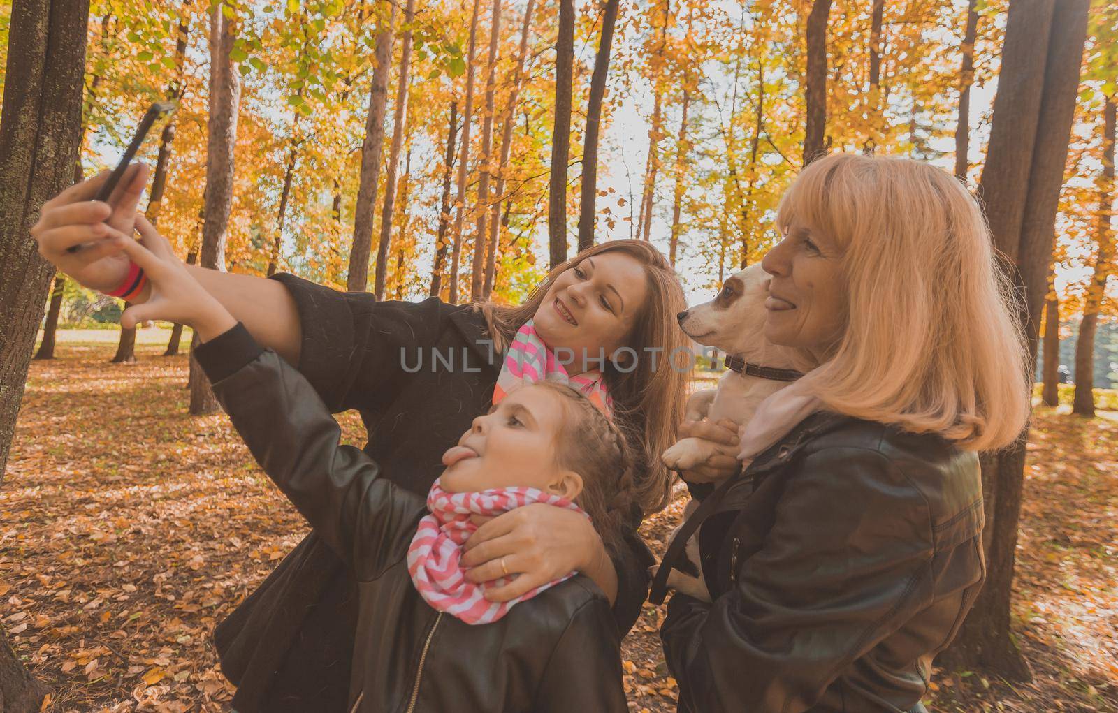 Three generations of women and dog feel fun look at camera posing for self-portrait picture together, funny excited child, mom and grandmother have fun enjoy weekend take selfie on gadget in autumn by Satura86