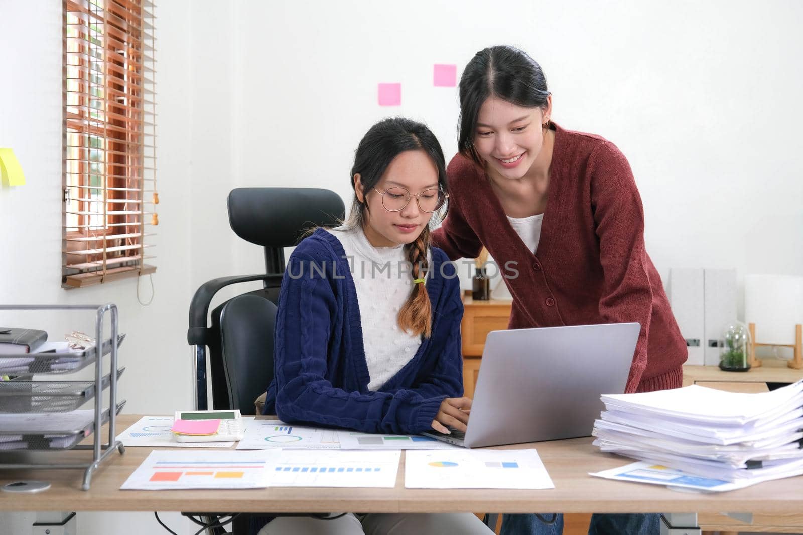 Two Young Asian woman discuss with new startup project Idea presentation, analyze planning and financial statistics and investment market at home. by wichayada