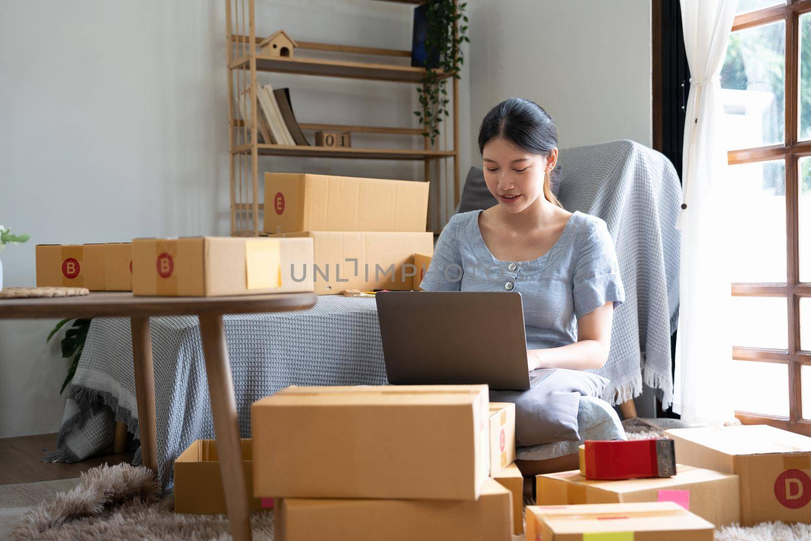 Start up small business, SME female owner checking order online to prepare to pack a box of goods for sale to customers, sme business idea