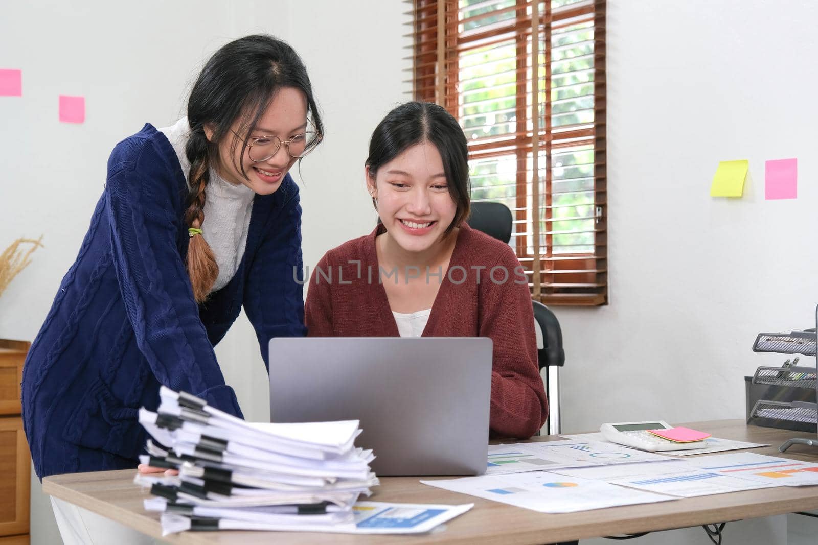 Two young Asian woman discuss with new startup project Idea presentation, analyze planning and financial statistics and investment market on laptop computer at home..