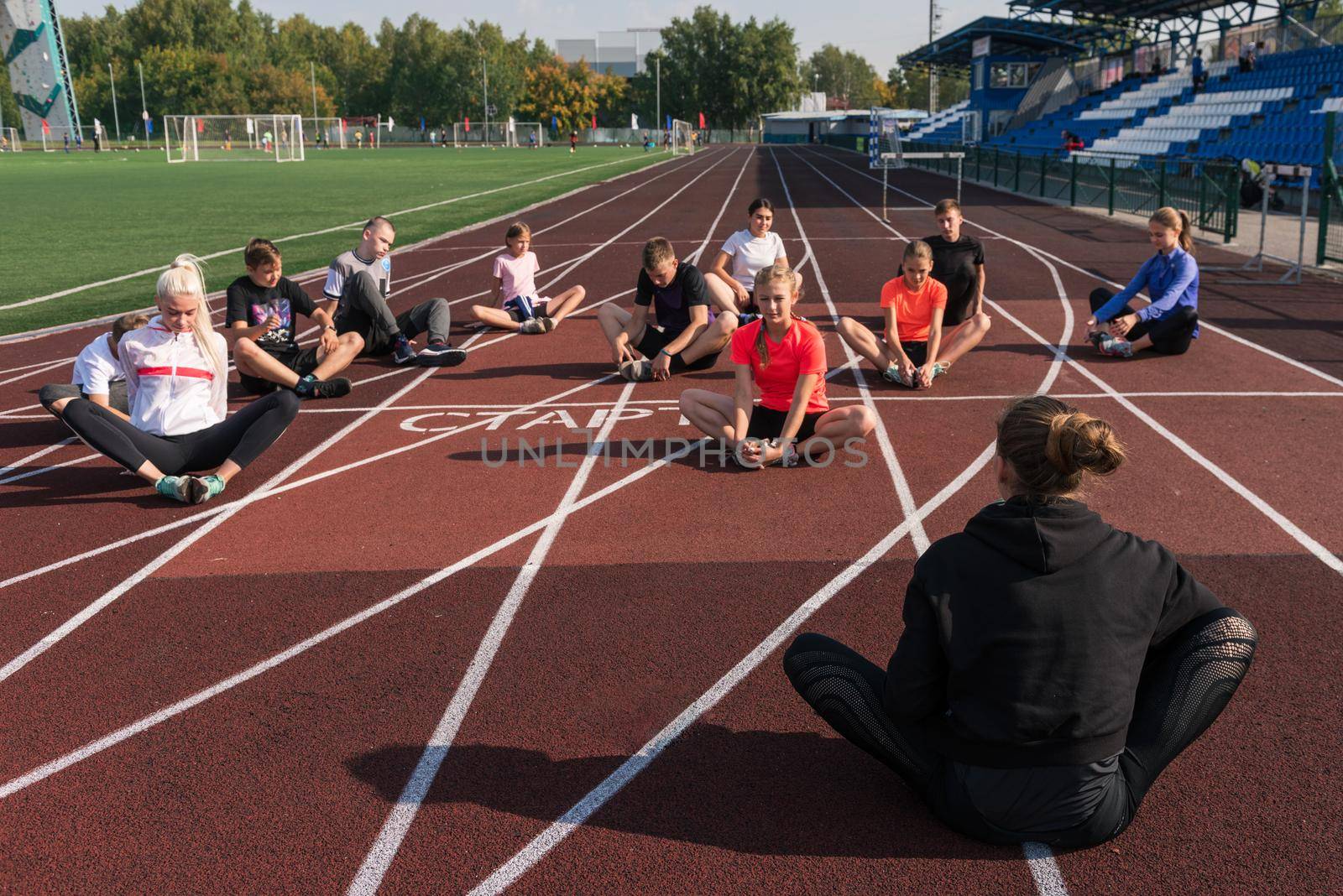 Female coach and group of children conducts a training session at the stadium. School gym trainings or athletics