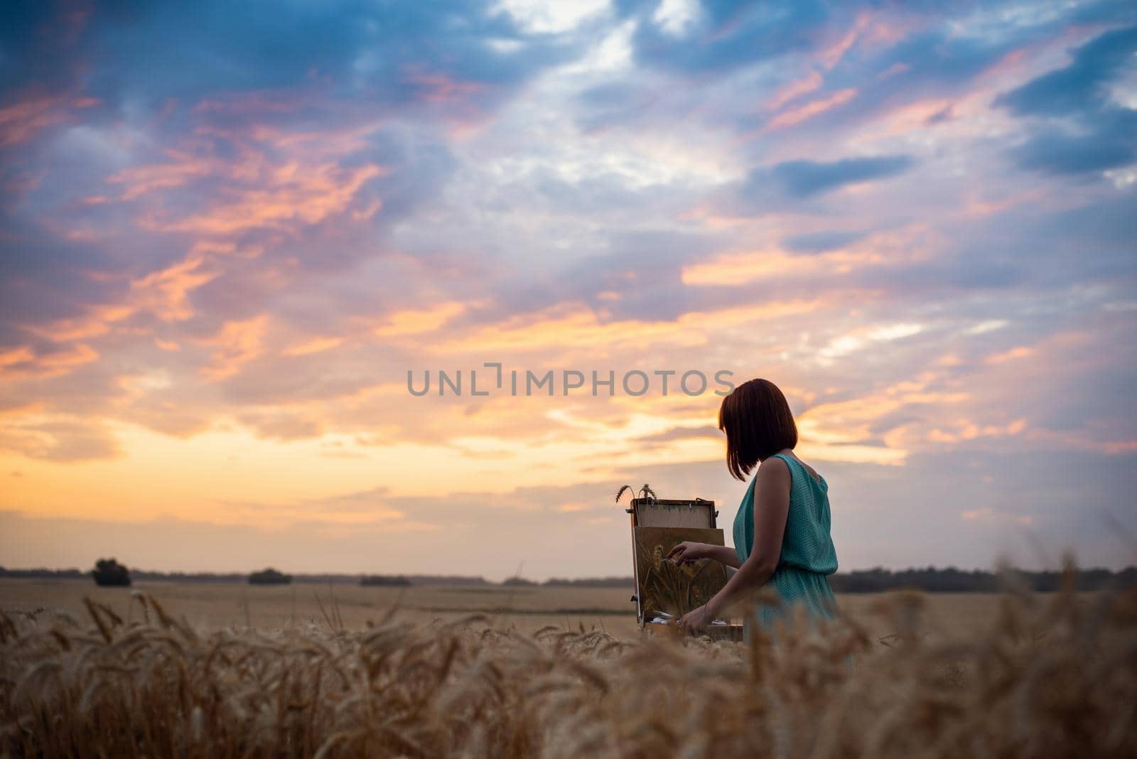 Female artist girl finishing her drawing in warm summer evening