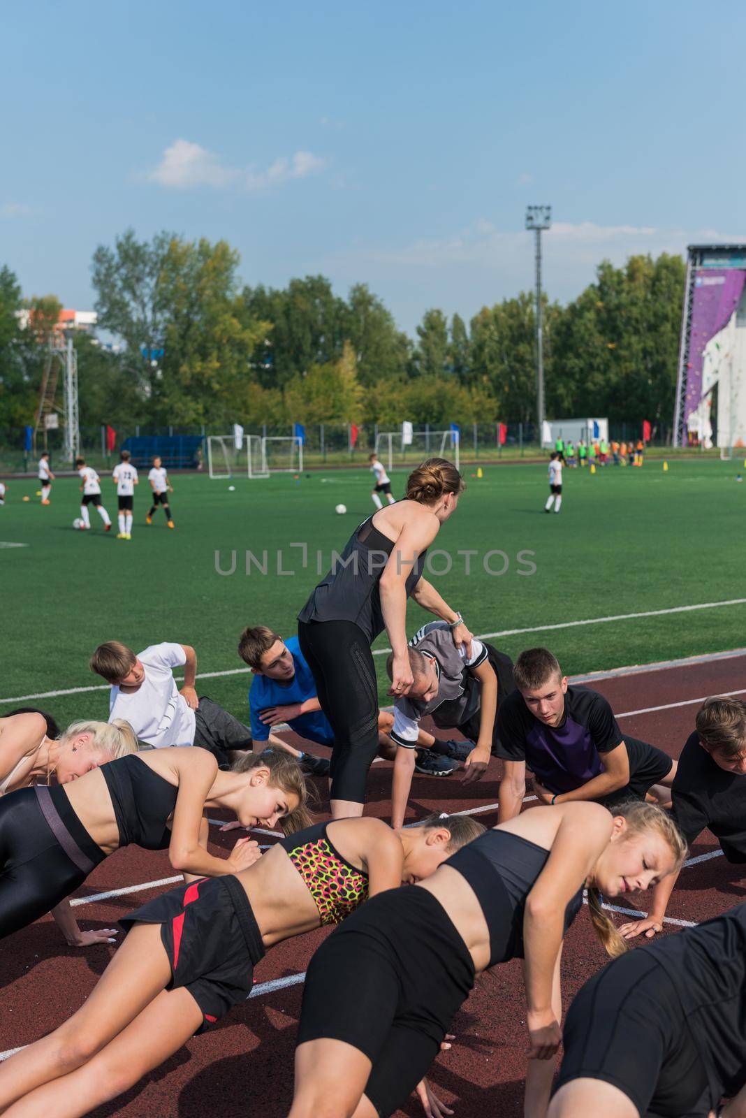 Female coach and group of children conducts a training session at the stadium. School gym trainings or athletics