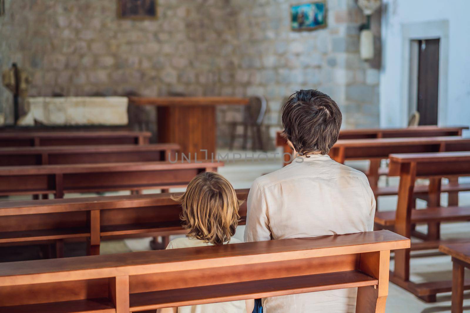 Christian dad tells his son Bible stories about Jesus sitting in kirk. Faith, religious education, modern church, father day, fatherly responsibilities, father influence on formation of son worldview.