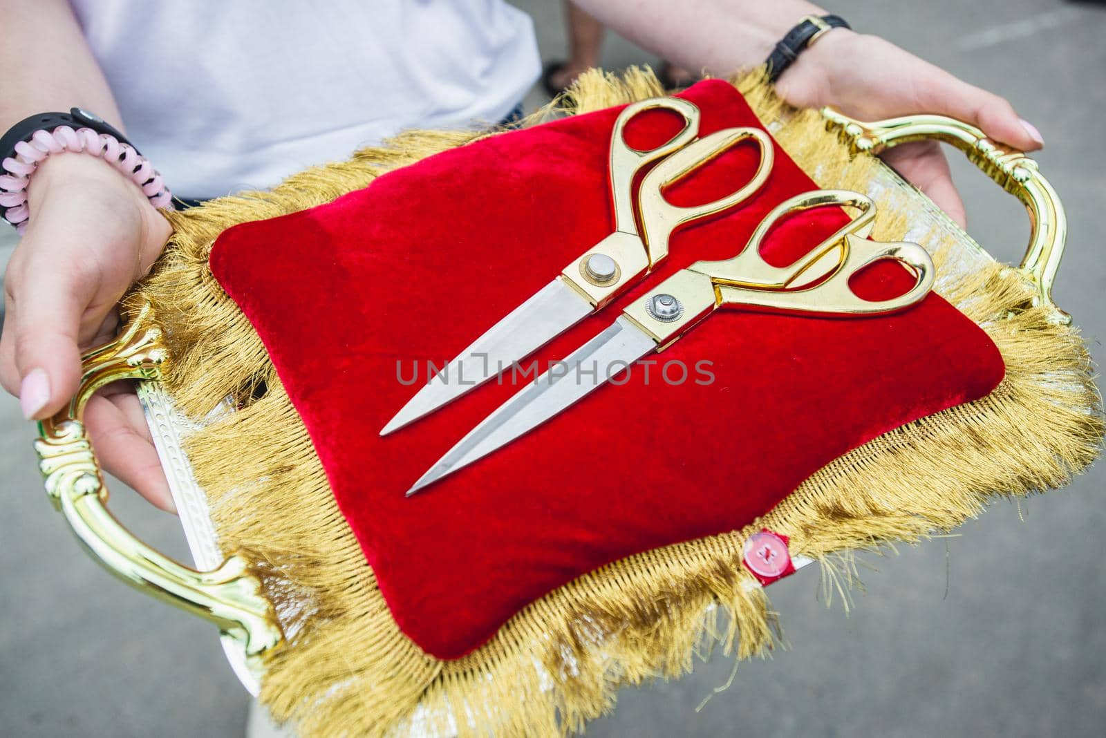 Golden scissors on red pillow in woman hands.