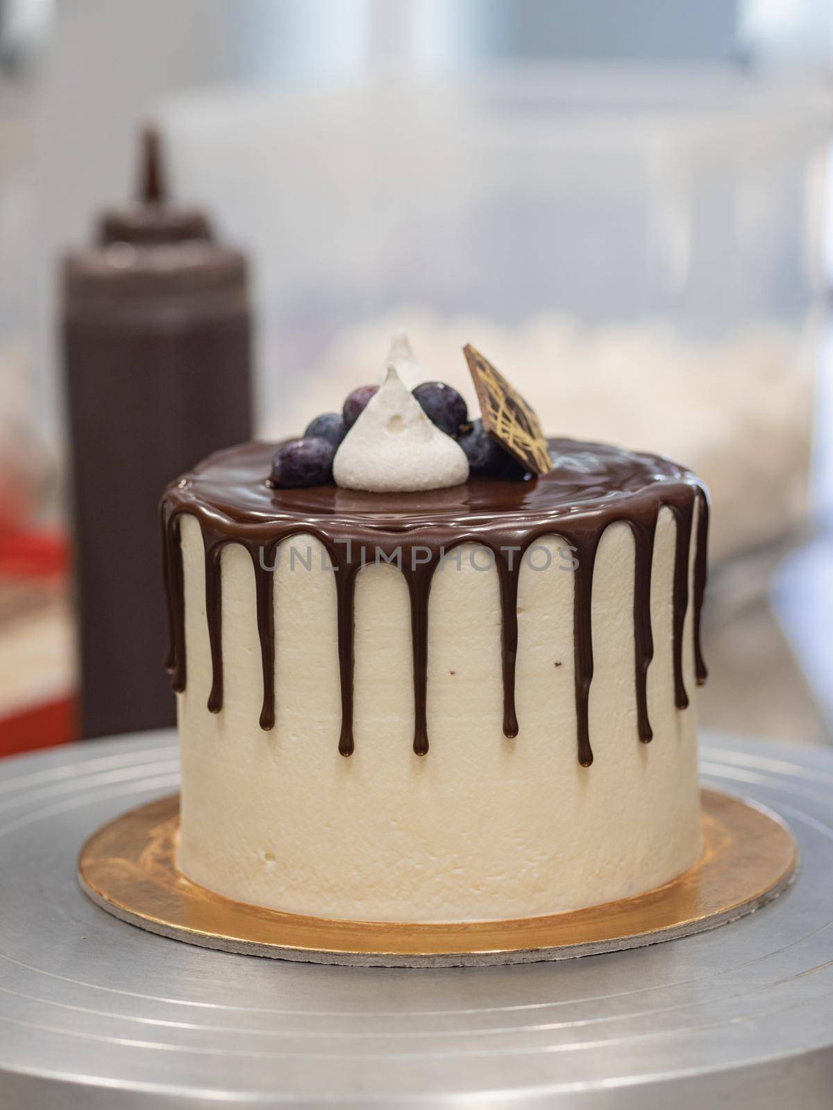 unrecognizable worker preparing a sweet dripping choco cake and berries