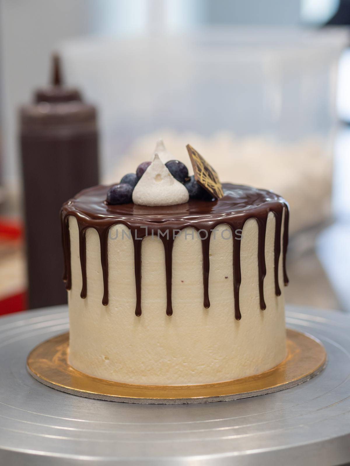 chocolate drip cake topping with gold cookie meringue and blueberries by verbano