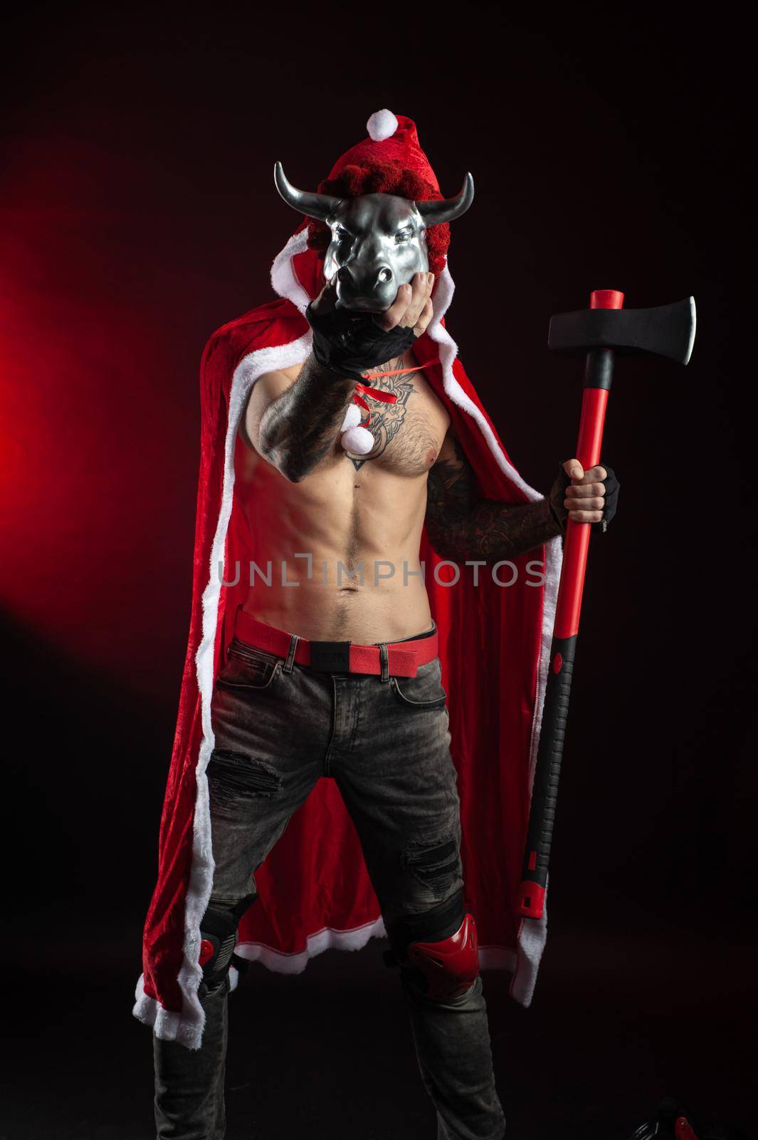 the man in a red Santa Claus Cape with an axe and a metal bull figurine symbol of the new year 2021