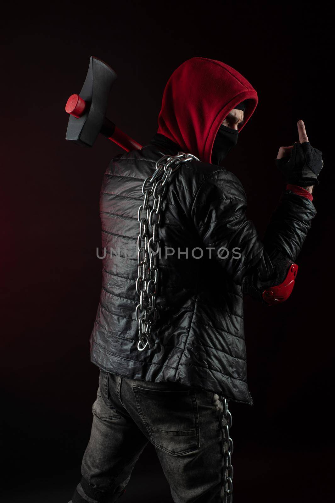 the a man in a Balaclava and hoodies with an axe the image of a Protestant shows the middle finger