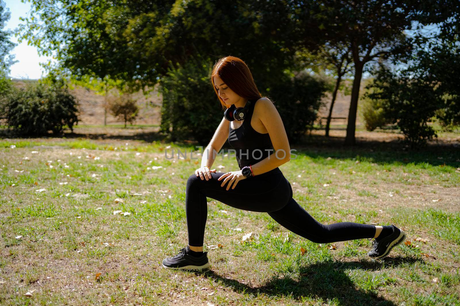 Redhead fitness woman doing lunge exercises for leg muscle training. by barcielaphoto