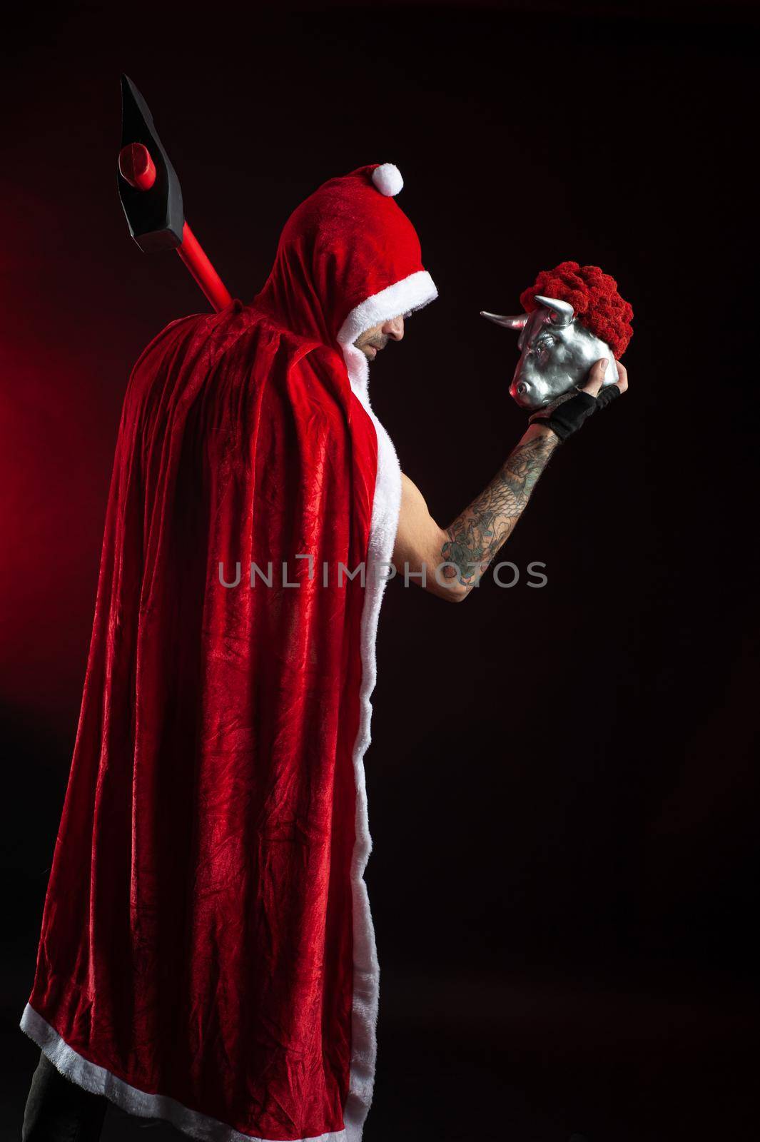 the man in a red Santa Claus Cape with an axe and a metal bull figurine symbol of the new year 2021