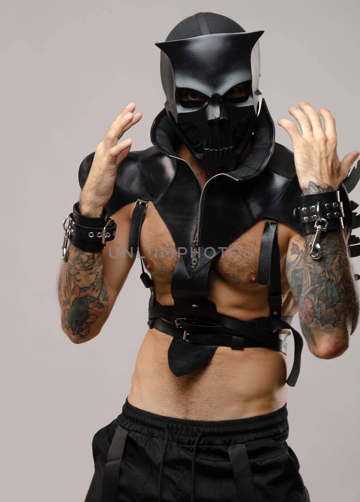 a man in a bdsm demon skull mask, dressed in a leather cloak with leather bracelets and straps on his body by Rotozey