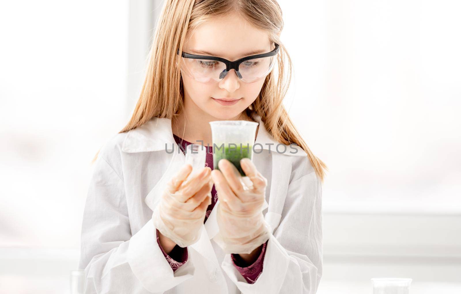 Girl doing scientific chemistry experiment wearing protection glasses. Schoolgirl with equipment and chemical liquids on school lesson