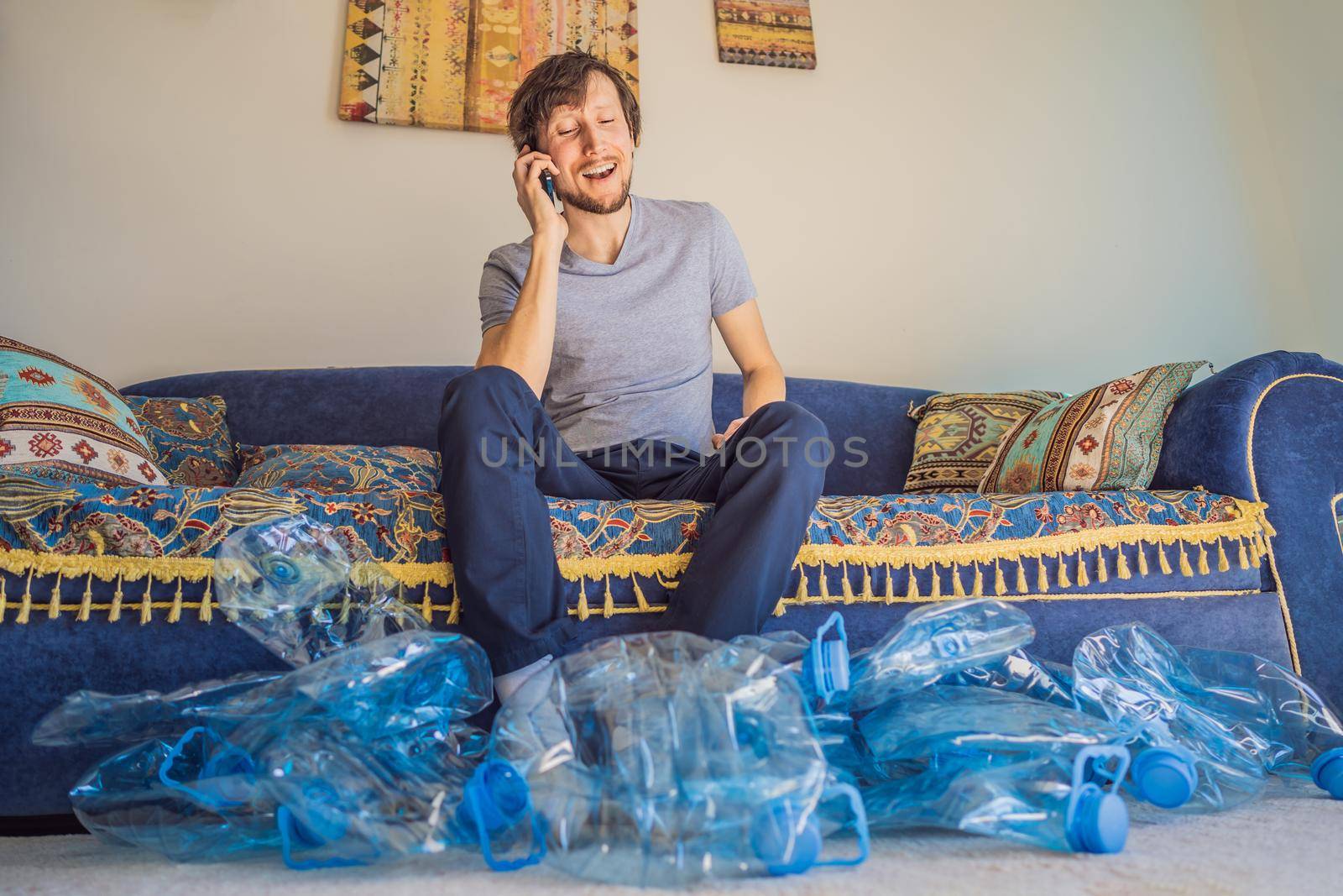 Young caucasian man hamong empty plastic bottles to recycle with sad expression.