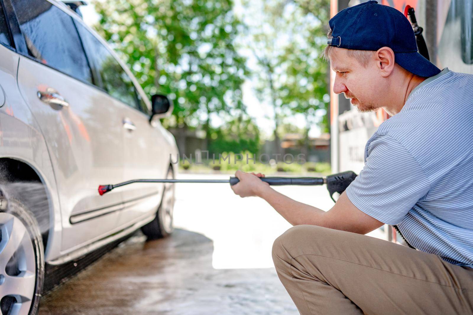 Shot of a man washing his car under high pressure water outdoors.