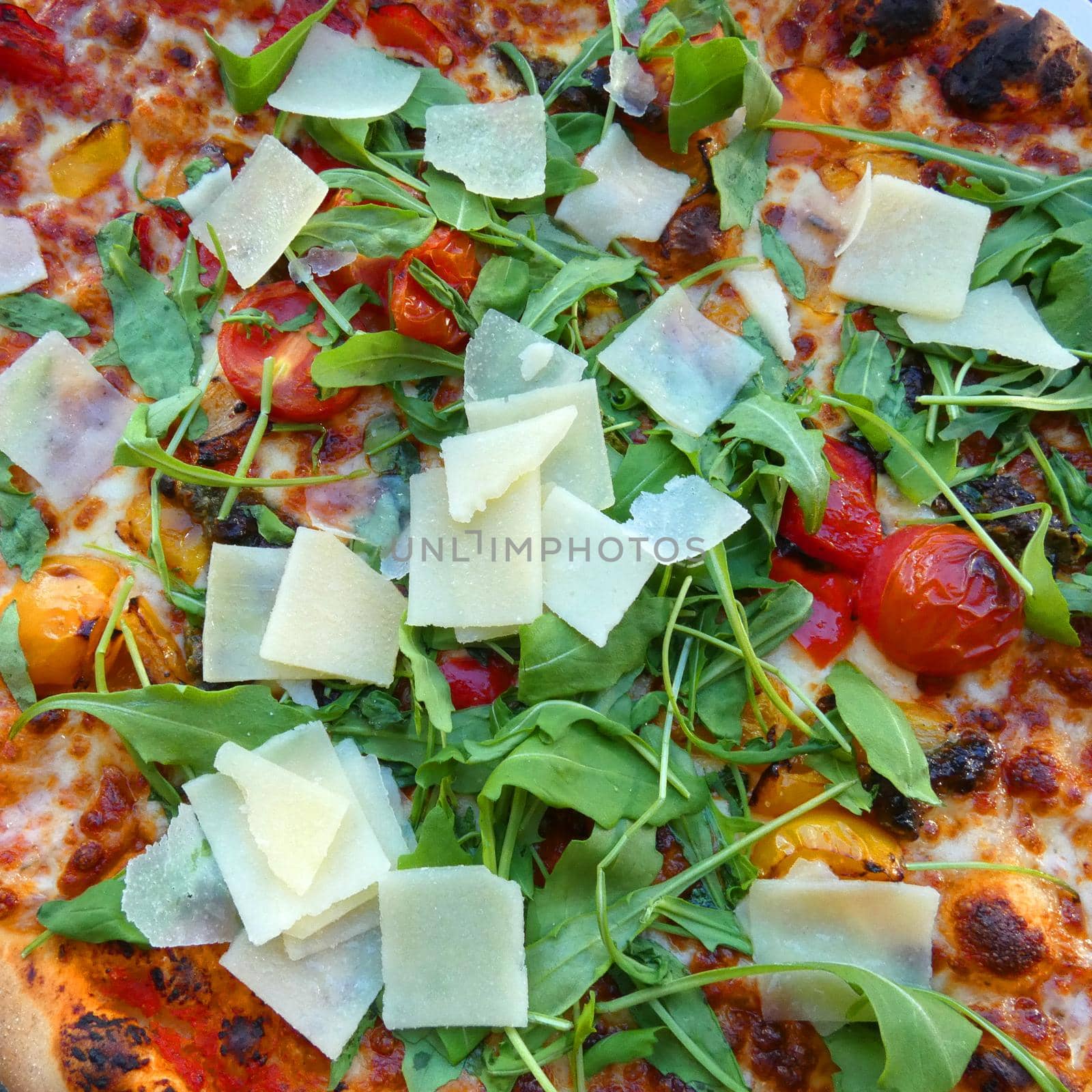 Vegetarian pizza with fresh ingredients: tomatoes, rucola salad, Parmesan cheese. Baked in a stone oven.