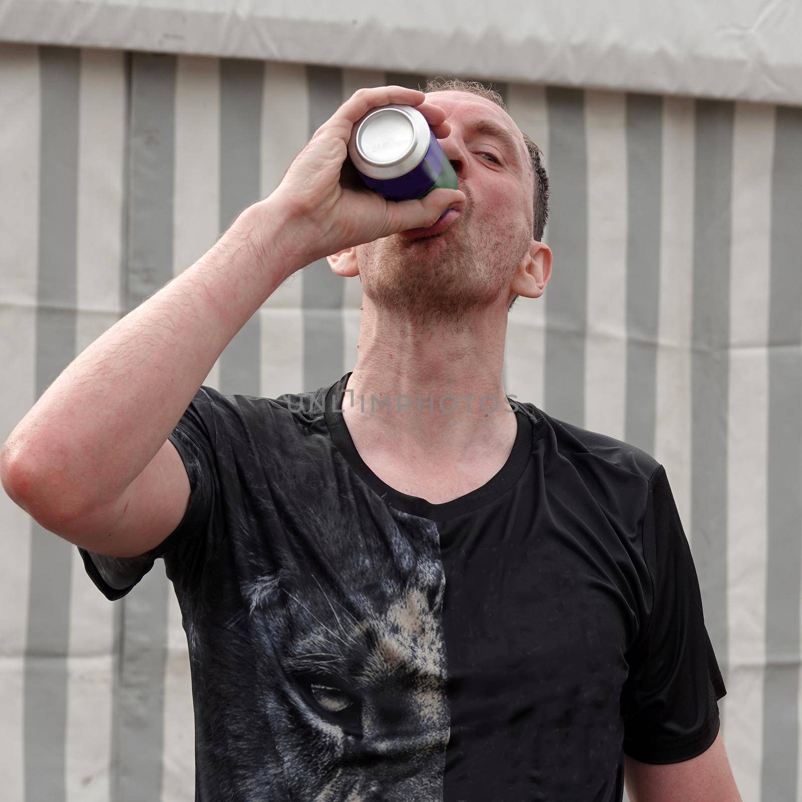 A cool drink after a heavy sports performance. Man drinking from a aluminum can. Hydration after running.