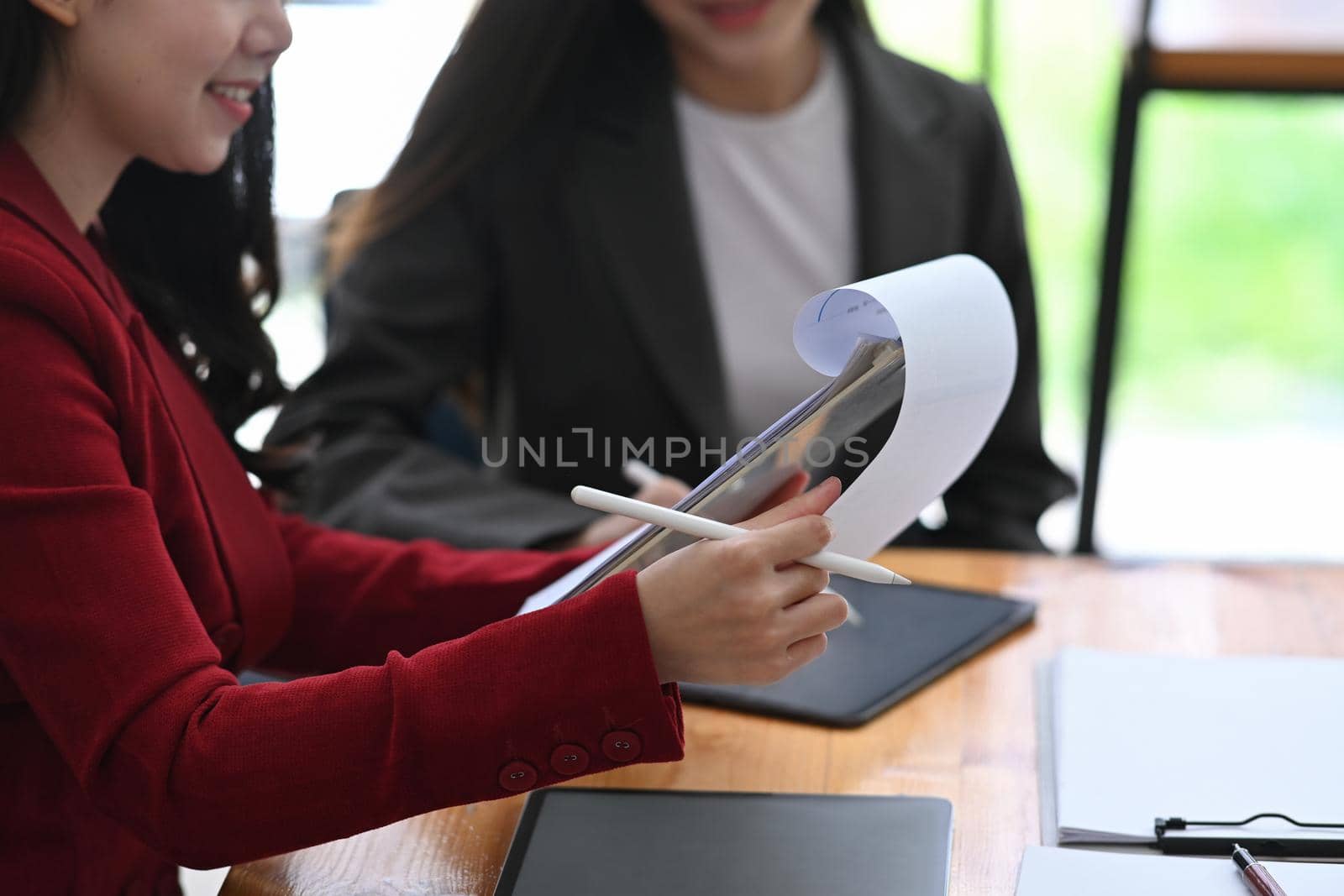 Businesswoman checking financial document while sitting with her colleague in office.