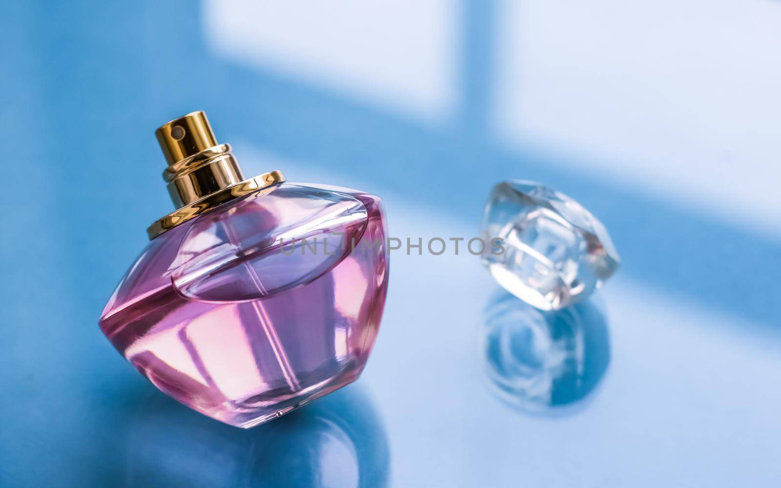 Perfumery, spa and branding concept - Pink perfume bottle on glossy background, sweet floral scent, glamour fragrance and eau de parfum as holiday gift and luxury beauty cosmetics brand design