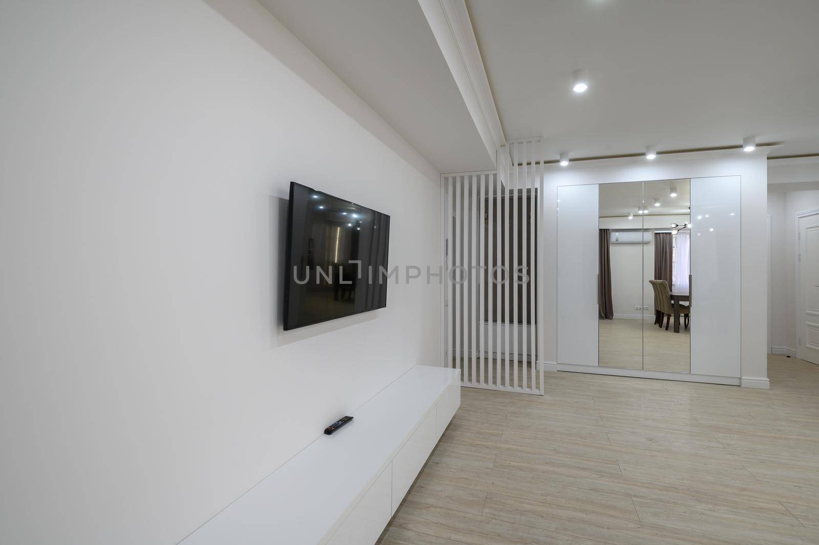 large white room connected to hall in a studio flat, flat screen tv on the wall