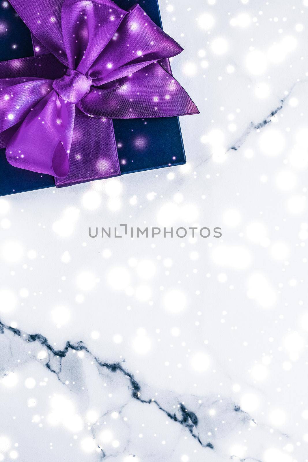 Branding, glamour and cold season concept - Winter holiday gift box with purple silk bow, snow glitter on marble background as Christmas and New Years presents for luxury beauty brand, flatlay design