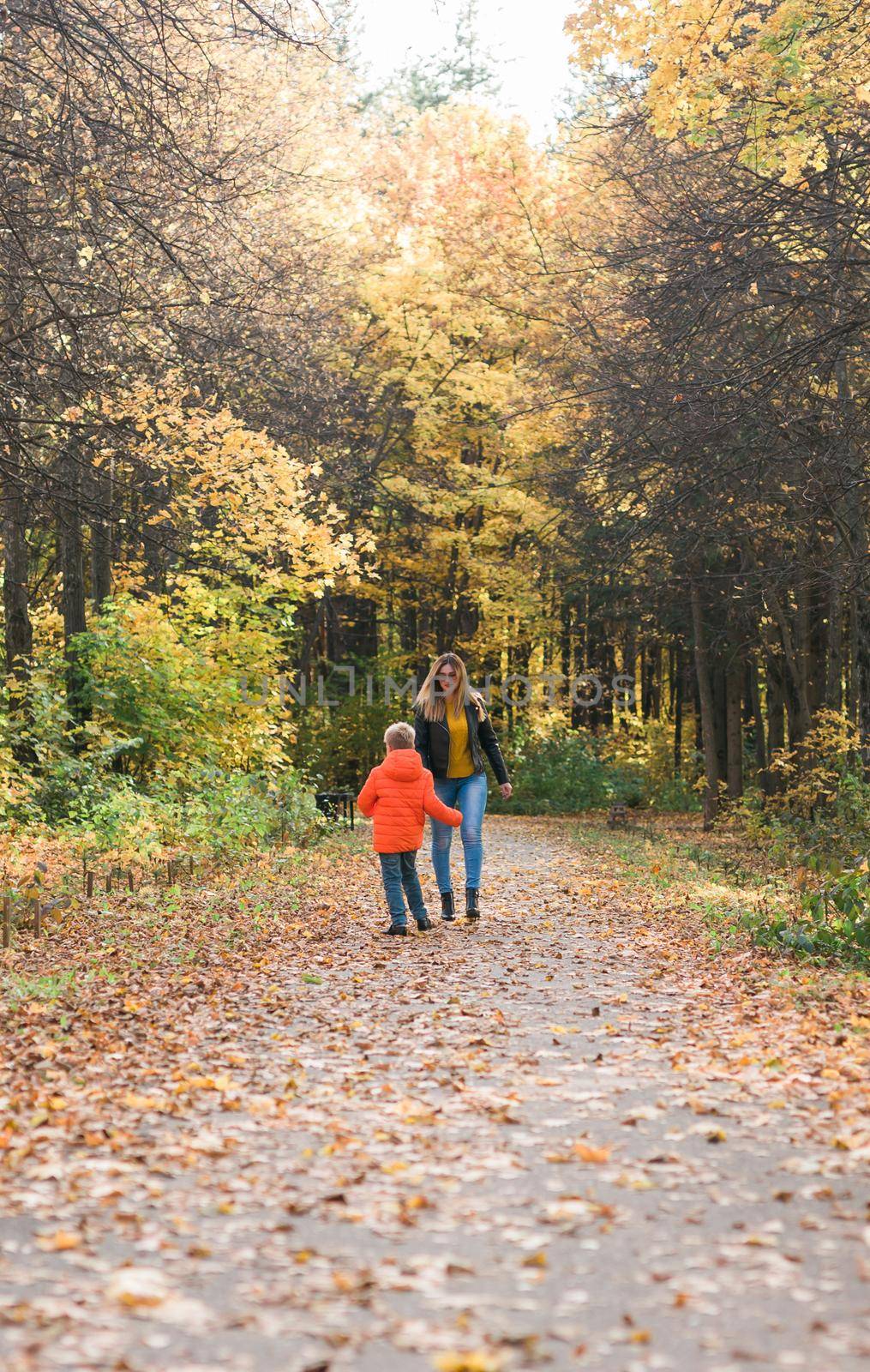 Mother and son walking in the fall park and enjoying the beautiful autumn nature. Season, single parent and children concept