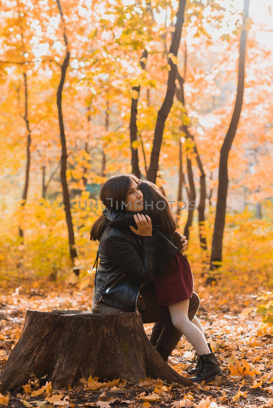 Mother and daughter spend time together in autumn yellow park. Season and single parent
