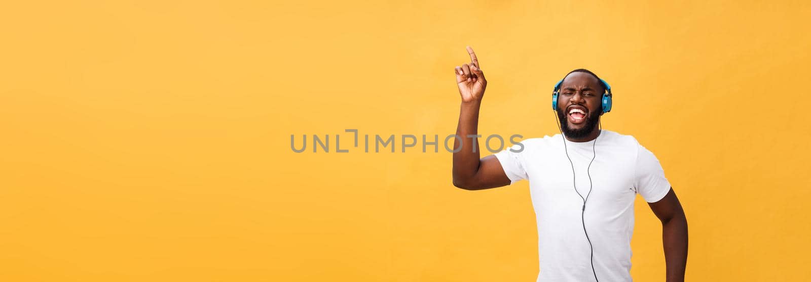 Young African American man wearing headphone and enjoy music dancing over yellow gold Background by Benzoix