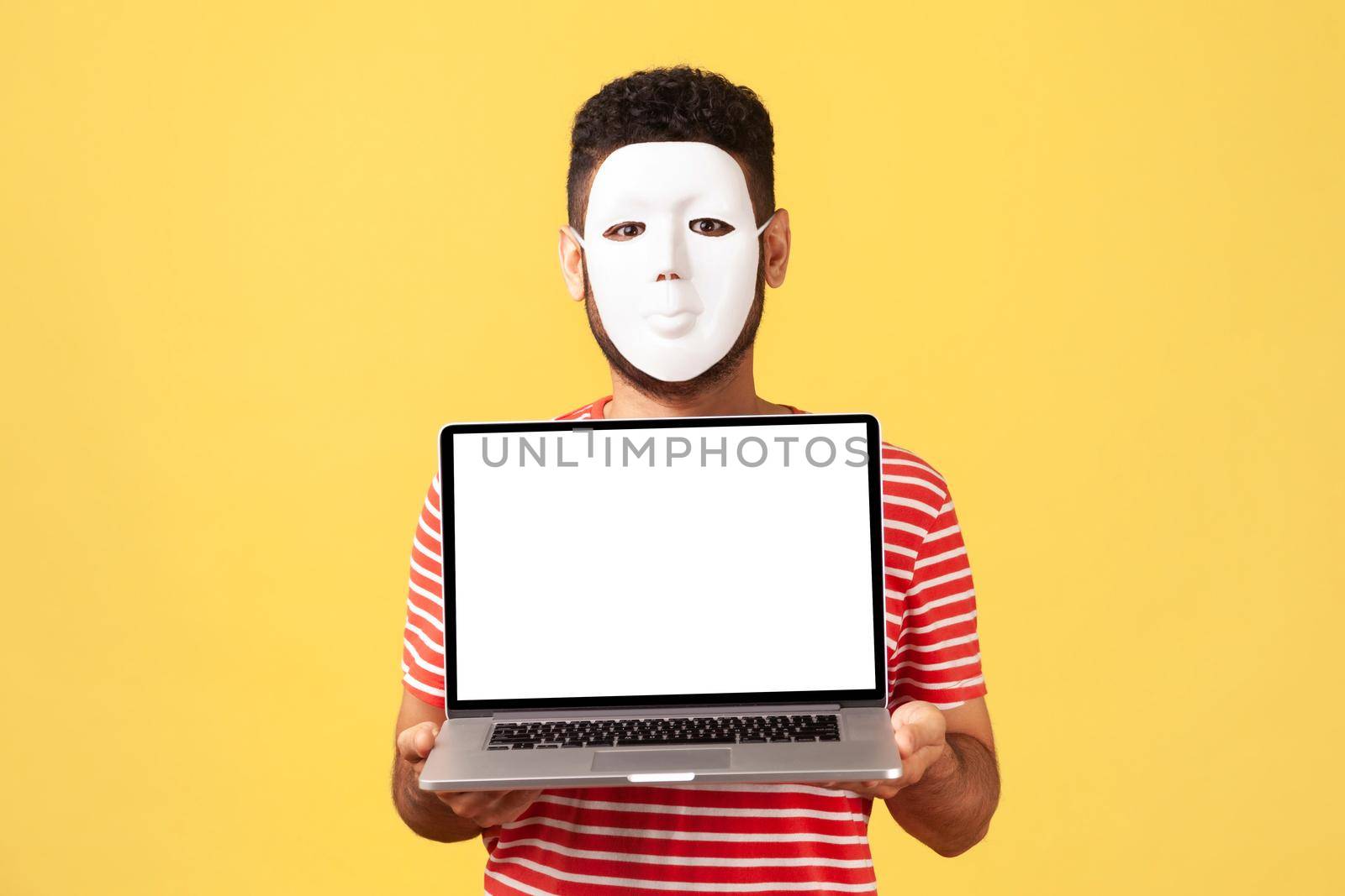 Unknown man in white mask hiding his real face and personality, holding laptop with empty display. by Khosro1
