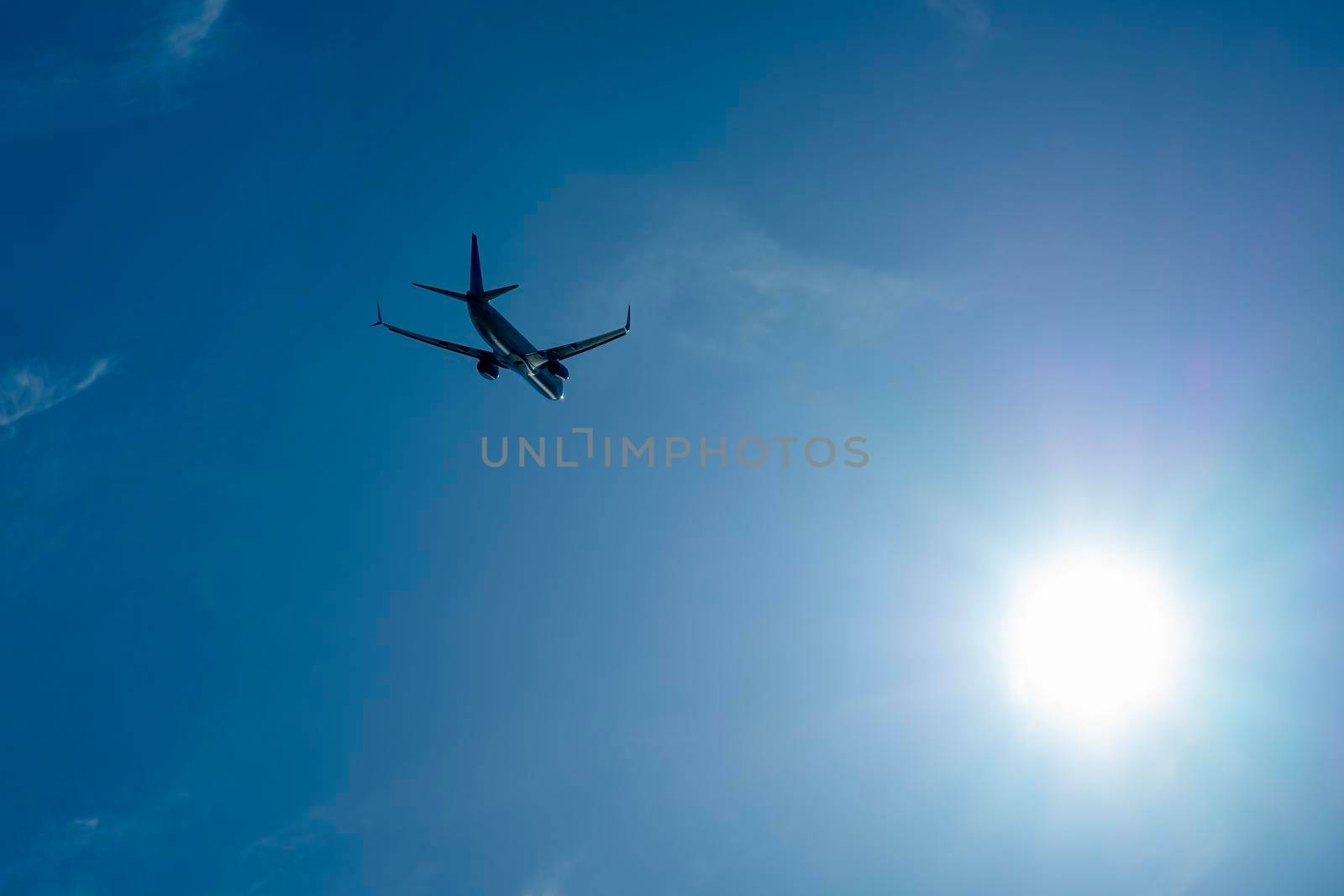 the plane is flying against a background of blue sky and sun by roman112007