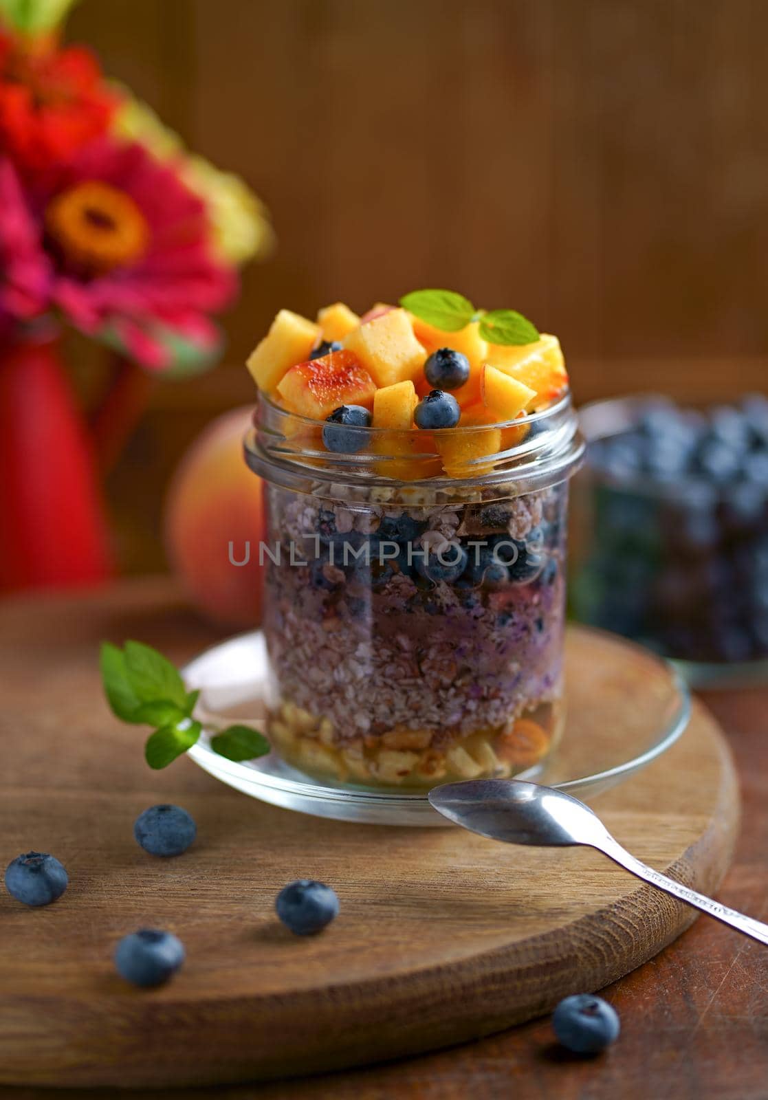 Healthy blueberries and raspberries parfait in mason jars, scene on dark rustic background by aprilphoto