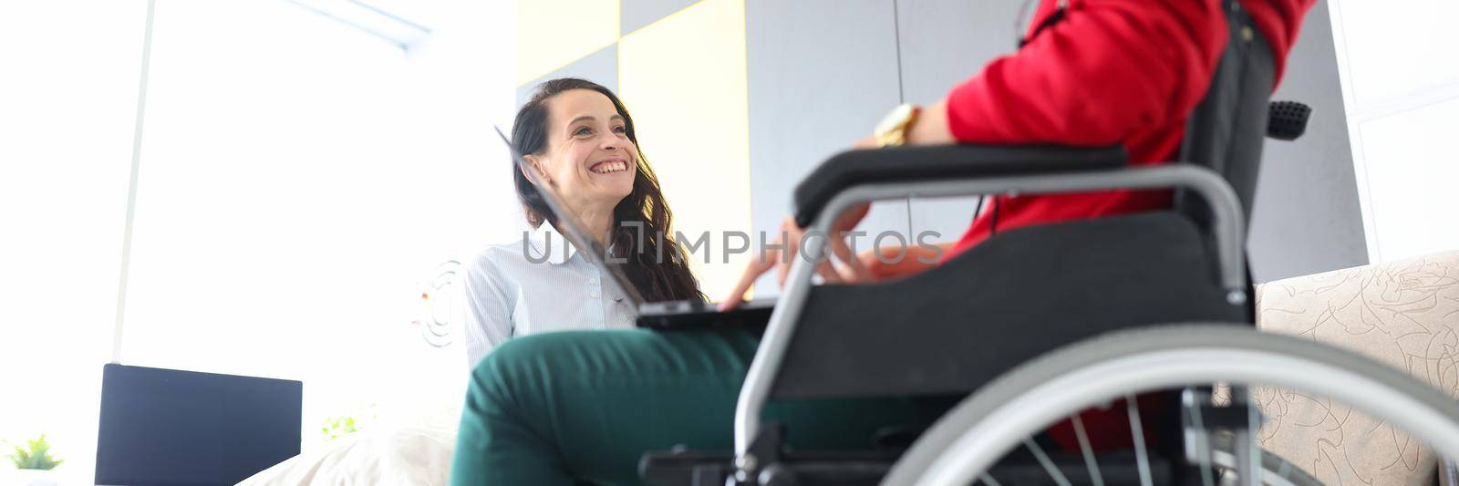 Woman in wheelchair communicates with friend at home. Positive communication with people with disabilities concept