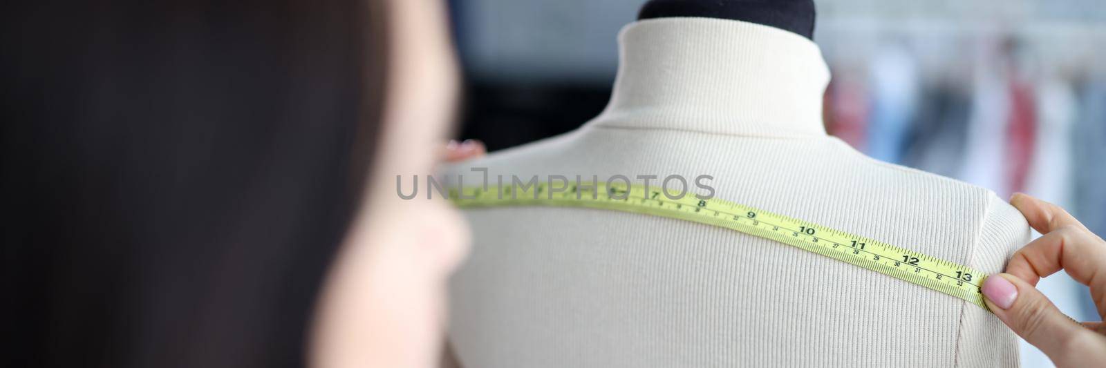 Woman fashion designer takes measurements with centimeter by kuprevich