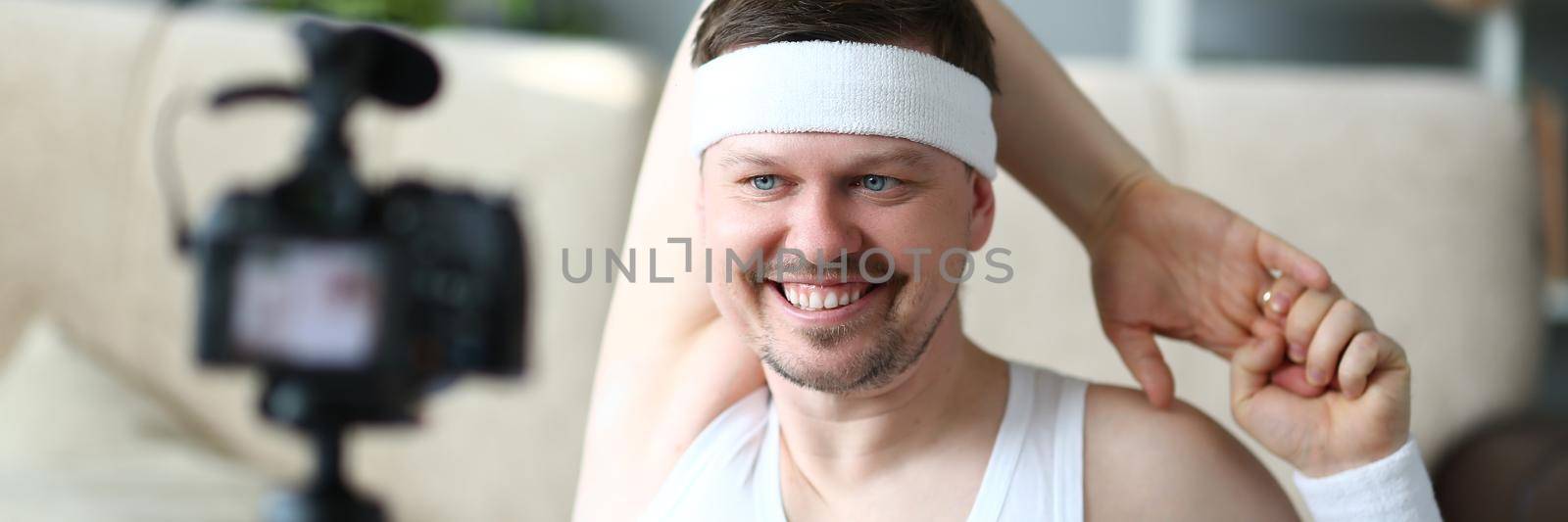 Smiling man doing sports exercises at camera. Remote training concept