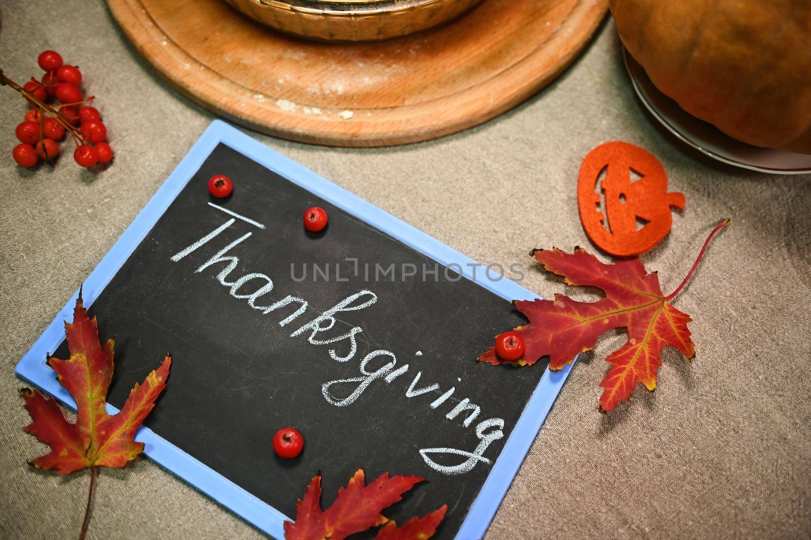 Selective focus on maple leaves and viburnum berries on a chalkboard with lettering Thanksgiving Day. Autumn still life by artgf