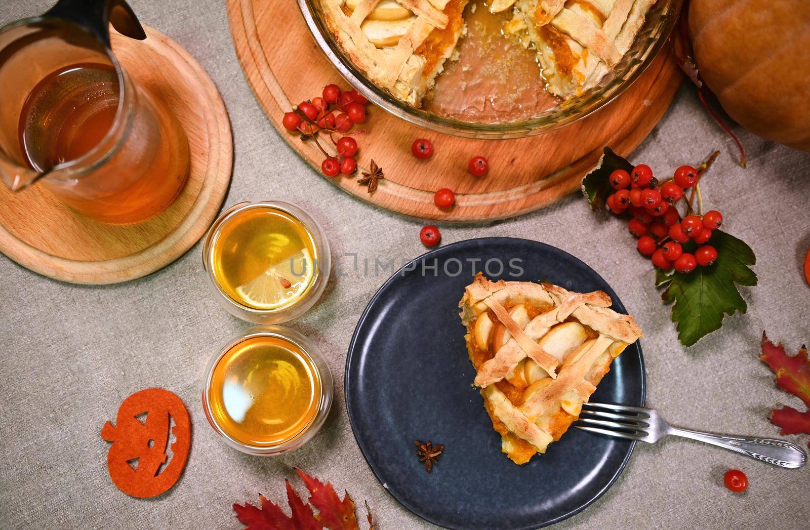 Top view. A piece of homemade sweet pumpkin pie with apples and crispy crust lattice and two cups of lemon tea. Tea time by artgf