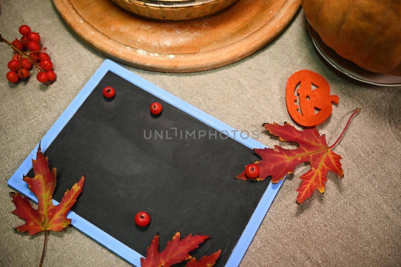 Top view chalkboard with copy advertising space, next to autumn maple leaves and branch of ripe red viburnum berries by artgf