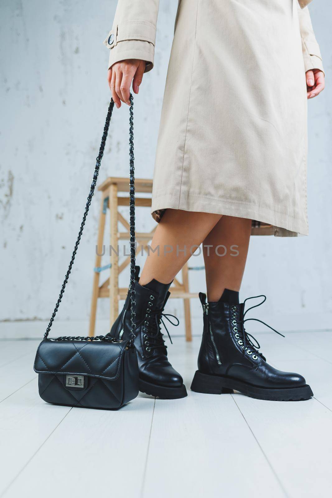 Close-up of female legs in black leather lace-up shoes. Black leather handbag in female hands. New autumn collection of women's leather shoes 2022