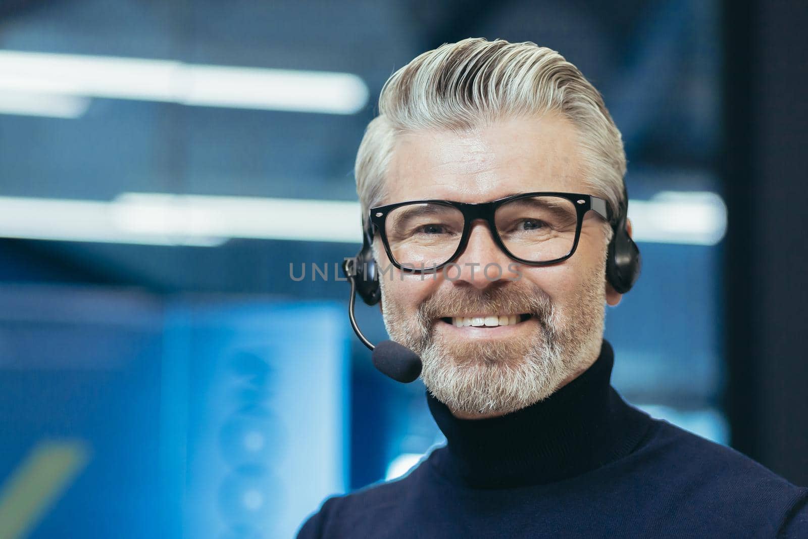 Portrait of a gray-haired handsome man in a headset with a microphone. Speaker, business trainer by voronaman