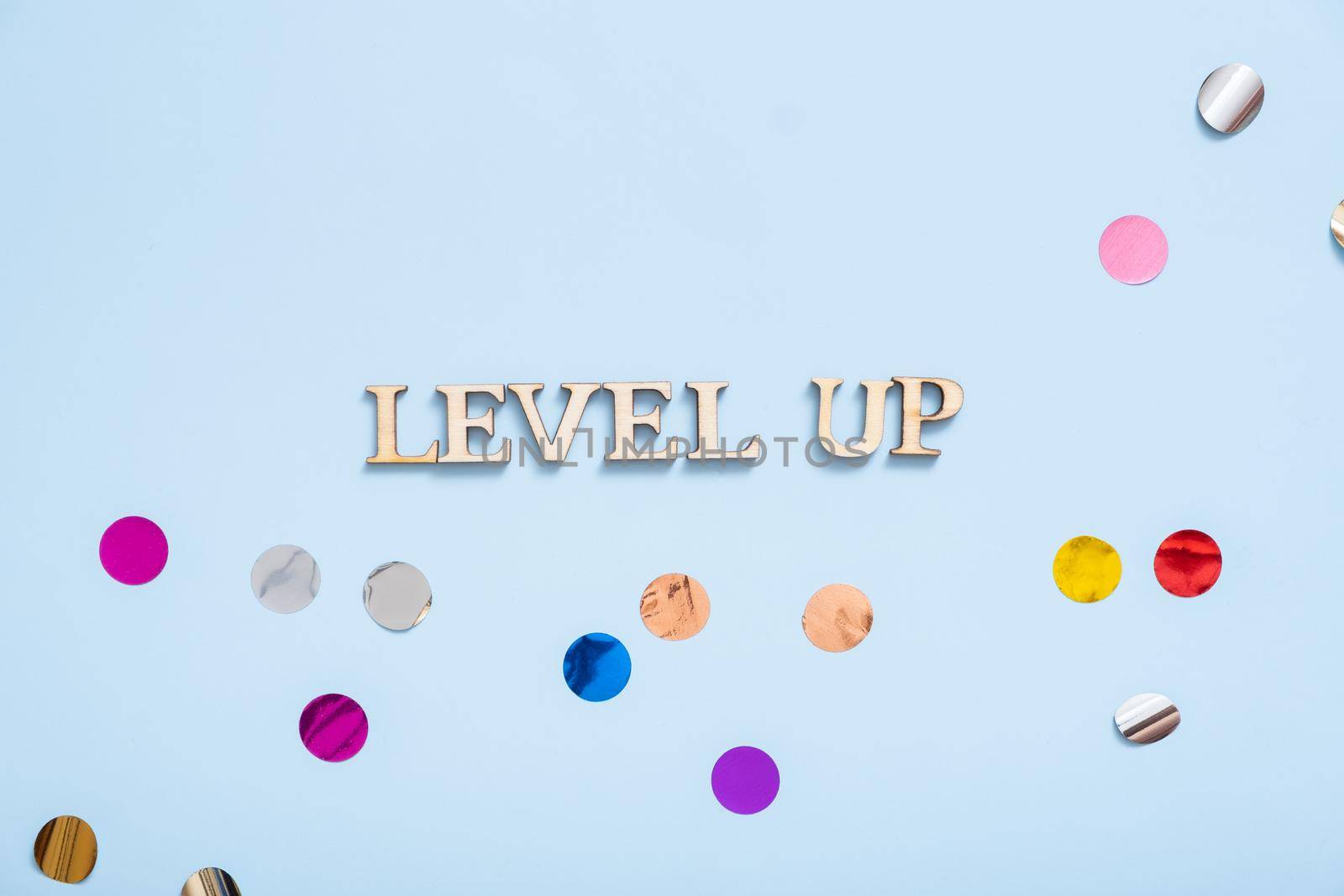 Level up wooden inscription on a colored background with tinsel. Achievement concept by ssvimaliss