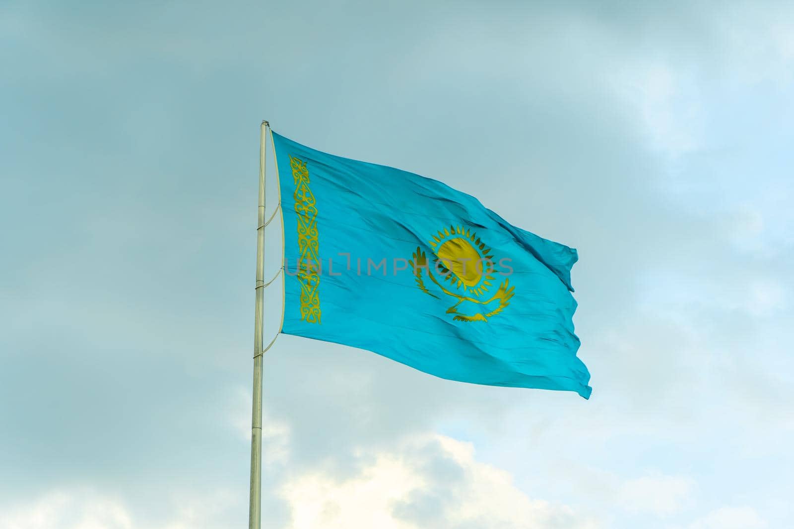 Flag of Kazakhstan on sky background. Waving flag of Republic of Kazakhstan. Fabric textures flowing flag of Kazakhstan.