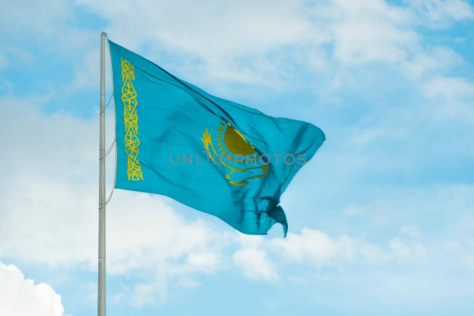 Flag of Kazakhstan on sky background. Waving flag of Republic of Kazakhstan. Fabric textures flowing flag of Kazakhstan. by YevgeniySam